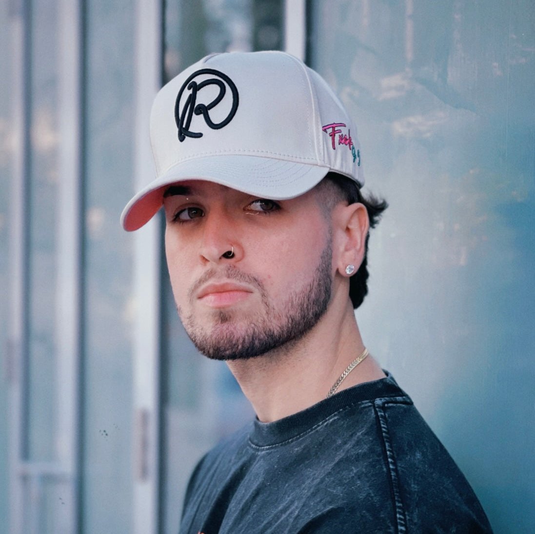 A person wearing a white baseball cap with a logo on the front, looking to the side.