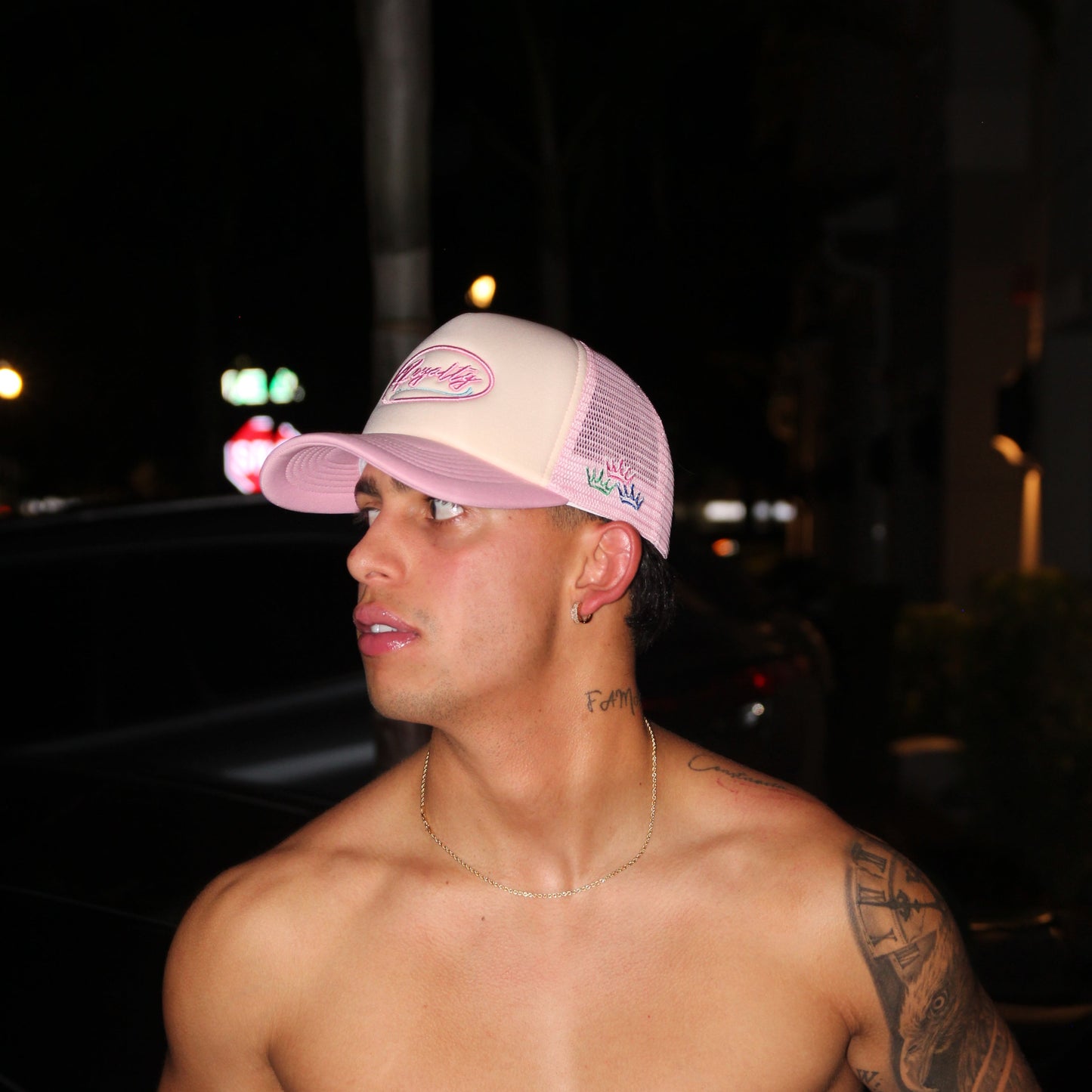Person with tattoos wearing a cap in a dark setting