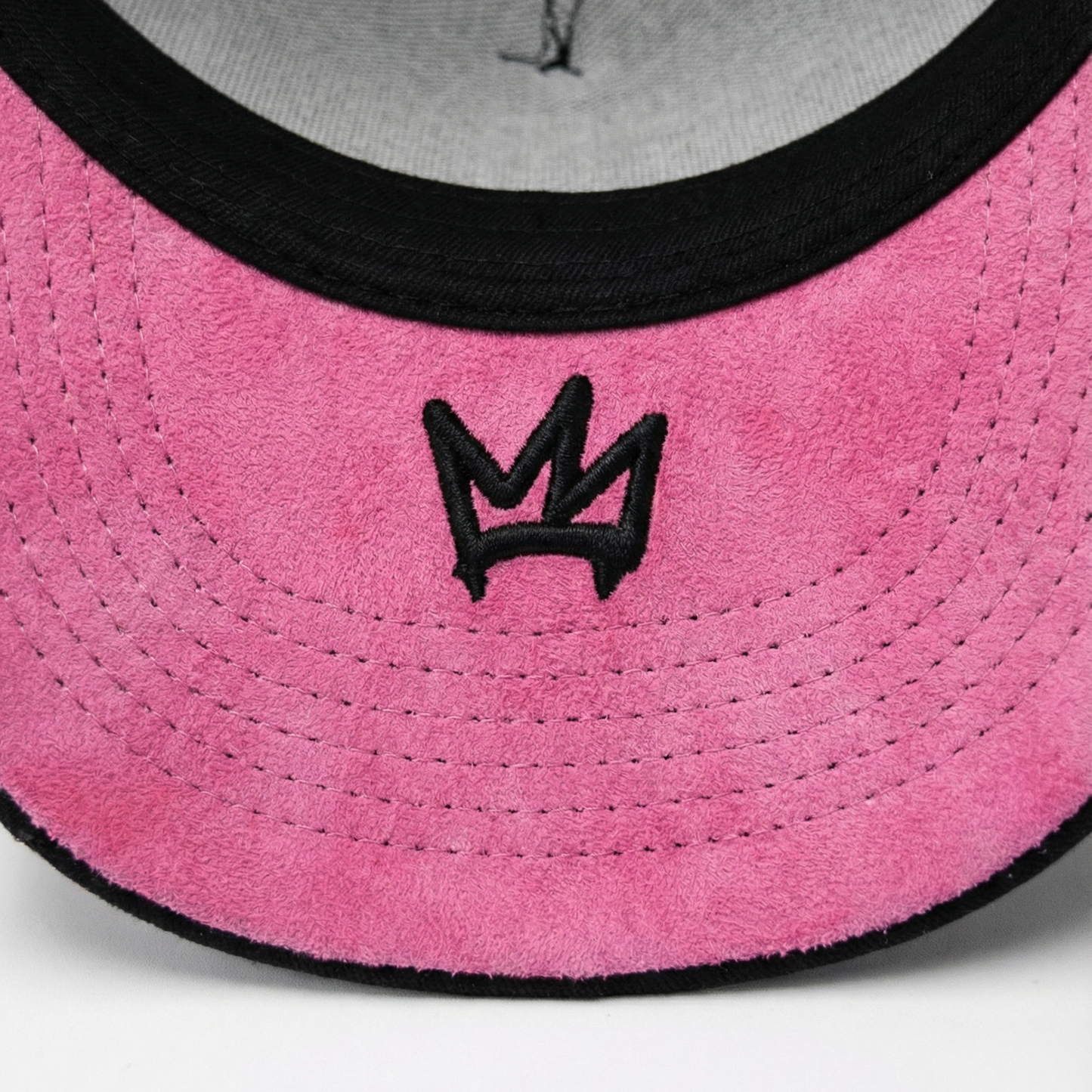 Close-up of a pink and gray cap with a black logo on a white background