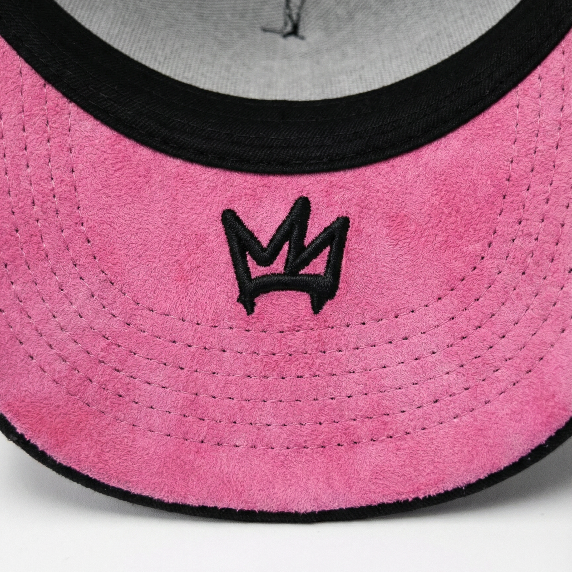 Close-up of a pink and gray cap with a black logo on a white background
