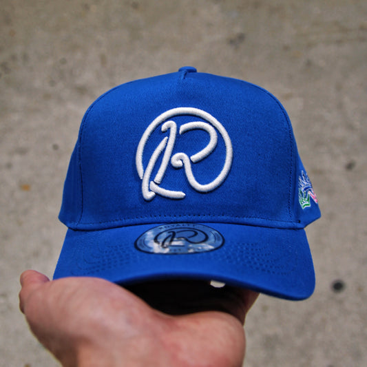 Blue cap with a white logo held by a hand against a concrete background