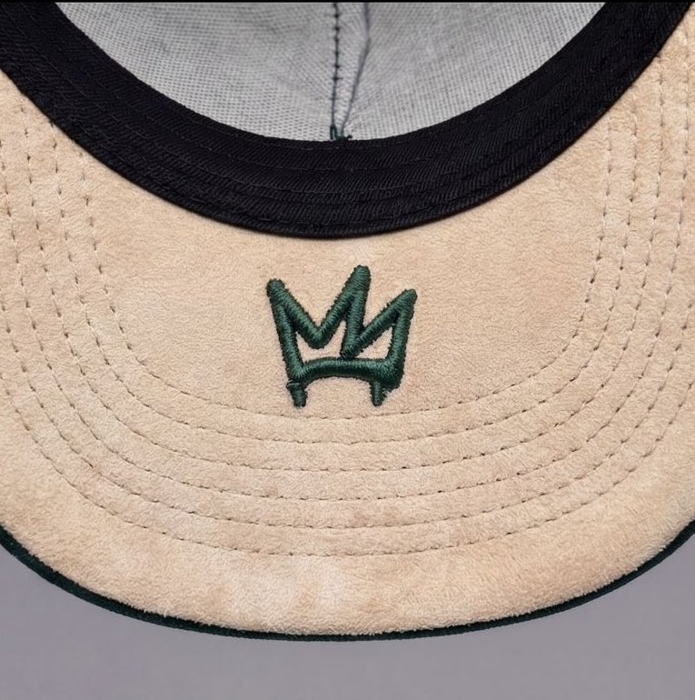 Green cap with embroidered designs and text on a gray background